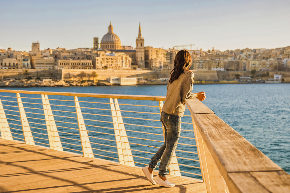 Young Asian woman overlooking the Valletta, Malta city skyline with colorful house balconies